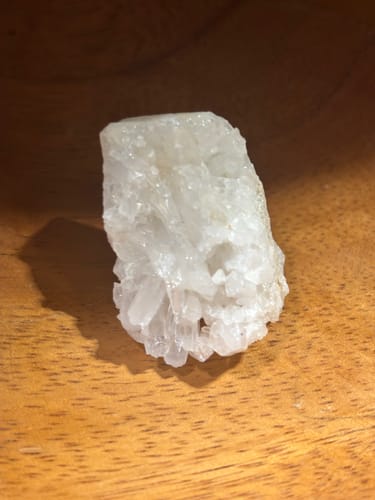 Customer's close-up of a clear quartz crystal cluster on a wooden surface.