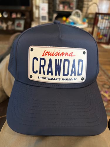 Customer's navy Louisiana Plate Hat featuring a white license plate patch customized with the word 'CRAWDAD'.