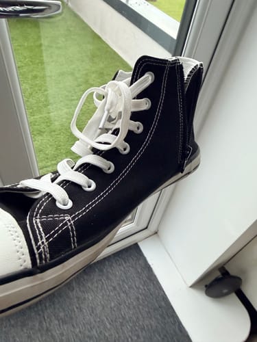 Customer's black high-top Roam I Barefoot Shoe held up, showing the white laces, sole, and side zipper.