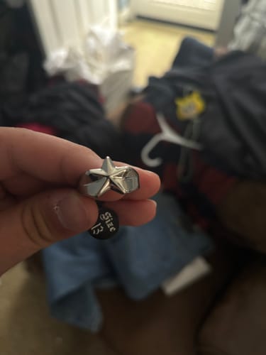 Customer holding up a shiny Star Ring with a size 13 tag visible.