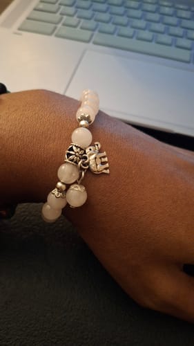 Reviewer's wrist wearing a rose quartz bead bracelet with a small silver elephant charm.