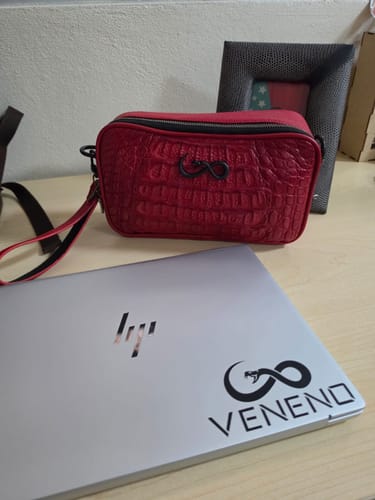 Reseñador muestra su Documentera roja con textura de cocodrilo sobre un escritorio de madera.