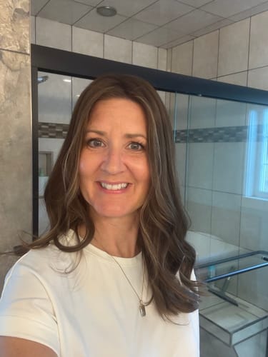 Reviewer smiling, showing the natural, wavy style of her Mocha Latte Lace Topper indoors.