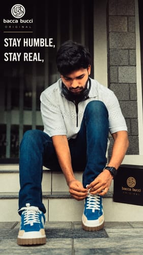 Reviewer tying the laces on a pair of blue METRO sneakers while sitting on outdoor steps.