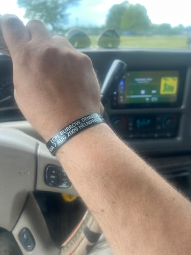 Customer wearing a black customized bracelet with white text on their wrist while driving.