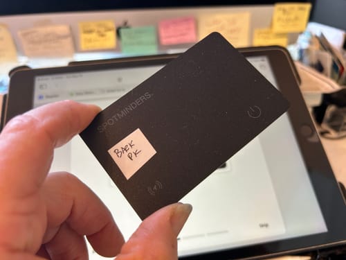 Customer holding the black SPOTMINDERS. Tracking Card in front of a tablet during setup.