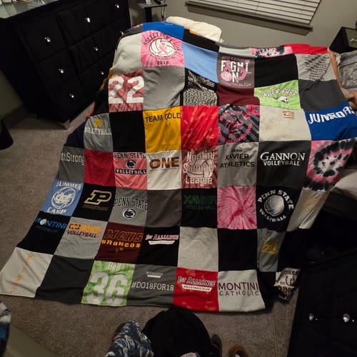 Customer's large Project Repat T-Shirt Quilt made from colorful school and sports t-shirts, spread across a bed.