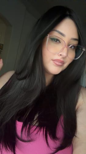 Customer wearing glasses, with the long, dark Natural Black Silk Topper styled smoothly over her shoulders.