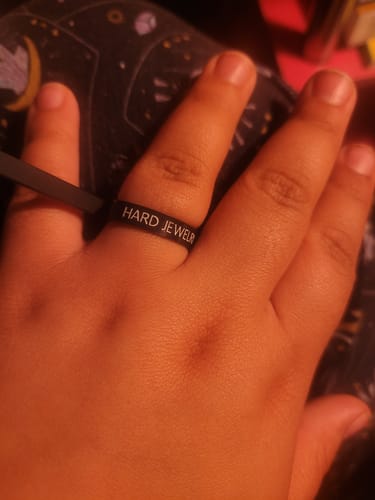 A customer's hand wearing the black Free Ring Sizer on their index finger to find their size.