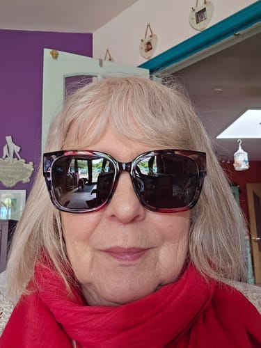 A reviewer wearing the large floral frame Polarized Fit Over Sunglasses indoors.