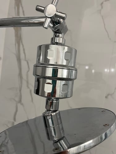 Customer's installed chrome shower filter, which holds the shower filter cartridge replacement, attached to a shower head.