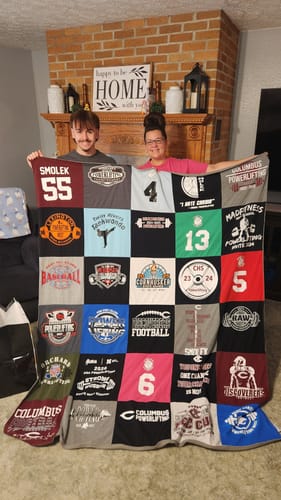 Customers holding up their colorful Project Repat T-Shirt Quilt made from dozens of different shirts.
