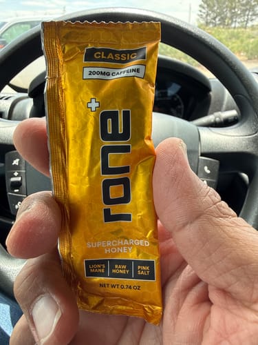 Customer holding a single golden packet of rone+ SuperCharged Honey in their car.