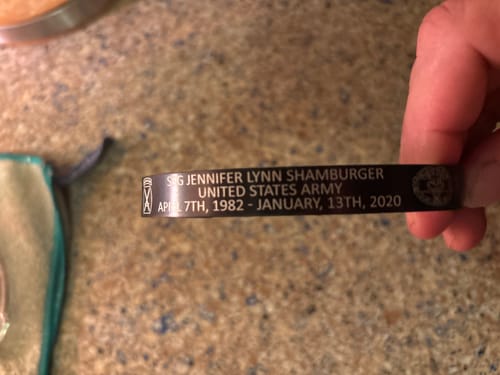 Close-up of a reviewer holding a custom black bracelet with memorial engravings.