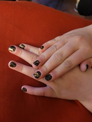Ein Kunde zeigt seine Hände mit den 'Black Magic Marble' UV-Gel-Nagelfolien in Schwarz und Gold.