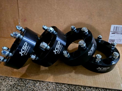 Reviewer's set of four black 2 Inch Wheel Spacers with attached studs, arranged on a cardboard box.