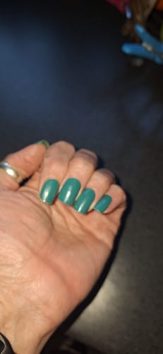 Customer's hand showing a full manicure with the shiny, emerald-colored Holy Gels.
