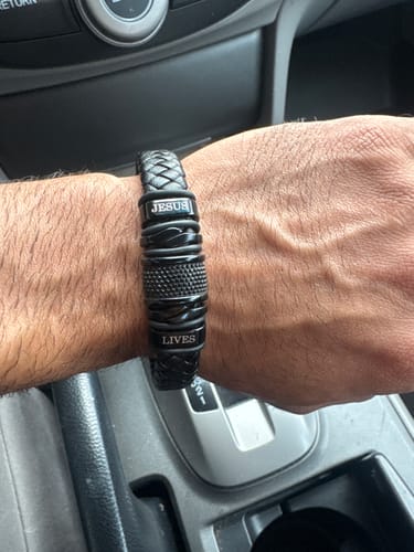 Customer wearing the black bracelet, personalized with the words 'JESUS LIVES', on their wrist in a car.