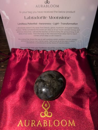 Customer's monthly crystal, a dark polished stone, displayed on a red pouch with its info card.