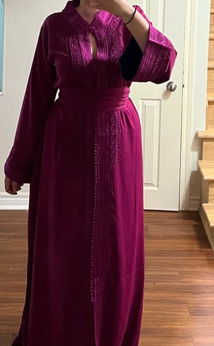 Reviewer wearing the magenta Caftan Nazeera with embroidery and a matching belt.
