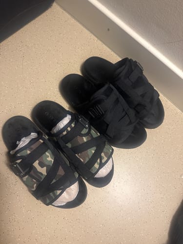 Customer's two pairs of Mystery DracoSlides on the floor, one with a camouflage print and one in all black.