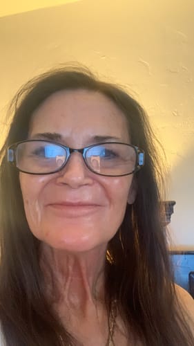 A close-up photo of a smiling reviewer with dark hair and glasses.