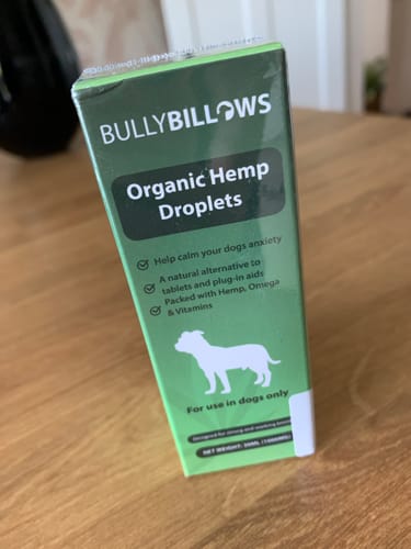 Reviewer's green box of BullyBillows Organic Hemp Droplets standing on a wooden table.