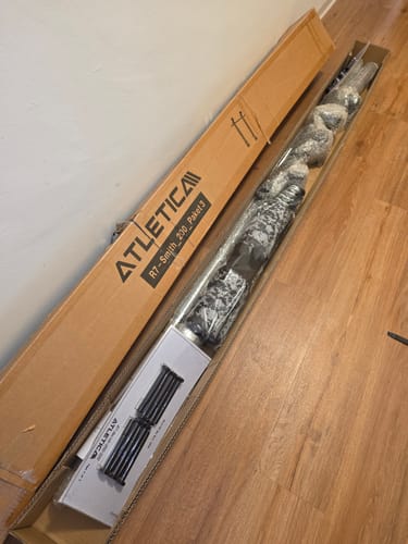 Kunde beim Auspacken des R7 Smith Option Paket 3, das auf dem Holzboden in der geöffneten Schachtel liegt.