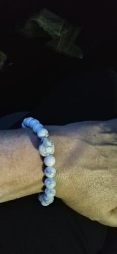 Close-up of a reviewer wearing a crystal bracelet with marbled light-colored beads on their wrist.