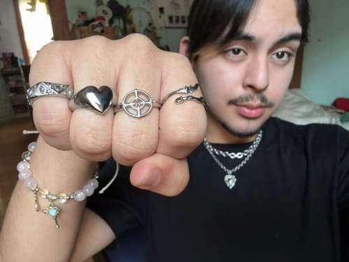 Customer showing their silver Crosshair Ring worn on their hand with other rings and necklaces.