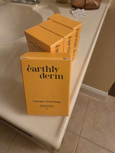 Reviewer's four new boxes of Turmeric Fade & Glow Bar on a bathroom vanity.