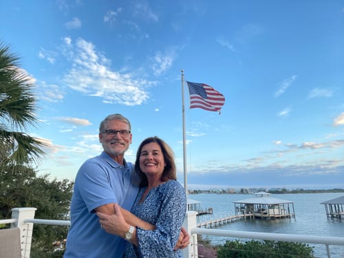 Reviewer with another person on a deck, with the Ultra Heavy Duty American Flag waving against a blue sky.