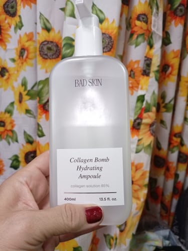 Reviewer holding the large, frosted bottle of Bad Skin Collagen Bomb Hydrating Ampoule.