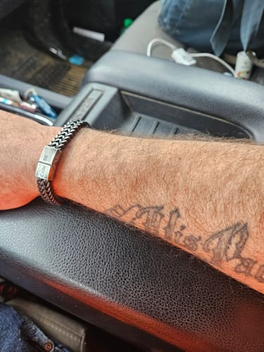 Close-up of a customer's arm wearing the stainless steel Knight's Creed Credo Bracelet in a car.