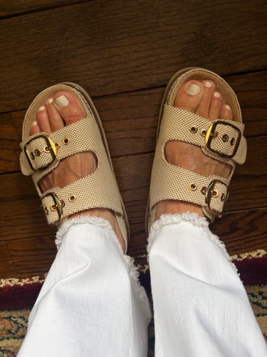 Customer's overhead view of the Corky's Cognac She's Spicy Sandals, worn with white frayed pants on a wood floor.