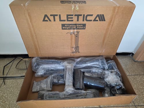 Rezensent zeigt den geöffneten Karton des R7 Latzug Stack Weight LOW_Paket 2 mit sicher verpackten Teilen.