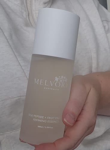 Customer holding the frosted bottle of SILK PEPTIDE + FRUIT ENZYME REFINING ESSENCE.