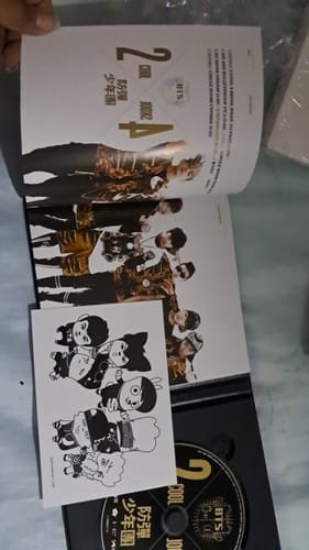 Customer holding open the BTS 2 COOL 4 SKOOL album, showing the photobook, CD, and an included illustrated card.