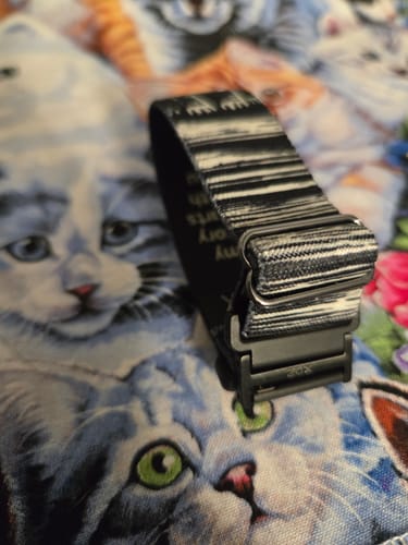 Close-up of a customer's black bracelet adapter converting a patterned watchband into a bracelet on a cat-print surface.