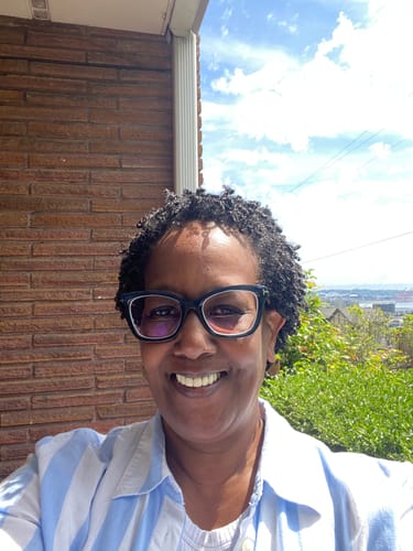 Reviewer smiling outdoors, showing clear, glowing skin after using the Turmeric Fade & Glow Bar.