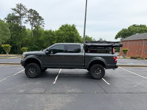 Reviewer's lifted dark grey truck parked in a lot, showing the improved stance after installation.