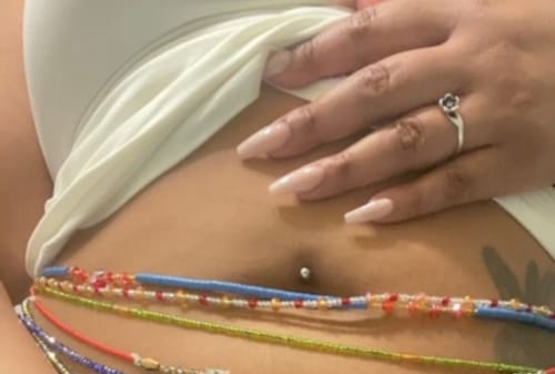 Close-up of a reviewer wearing a stack of waist beads, with the blue and red Blue Lotus strand at the top.