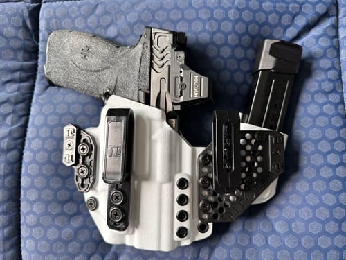 Reviewer's white APX holster holding a handgun and an extra magazine on a blue patterned surface.