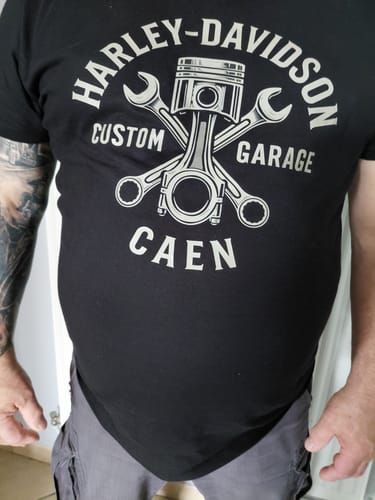Client portant un t-shirt noir à motif graphique pour montrer la coupe et la qualité du tissu.