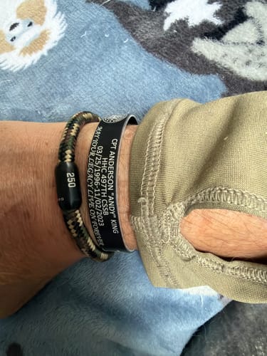 Customer wearing their black customized memorial bracelet on their wrist, showing the engraved text.
