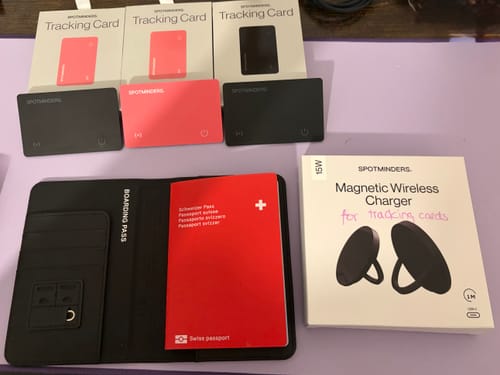 Reviewer's SPOTMINDERS Wireless Charger box shown with the tracking cards and passport holder it is designed to charge.