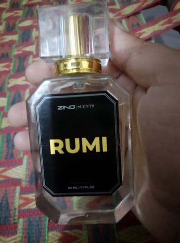 A customer holding the Rumi perfume bottle, showing its black label with gold text.