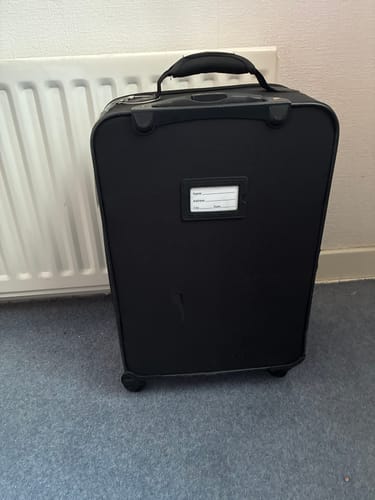 Customer's small black carry-on suitcase, which they are tracking with the SPOTMINDERS Tracking Card.