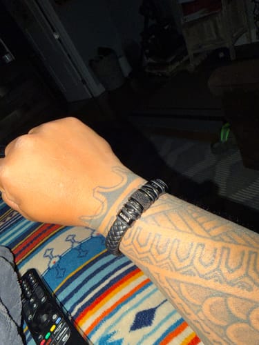 Customer's tattooed arm showing the perfect fit of the solid black bracelet.