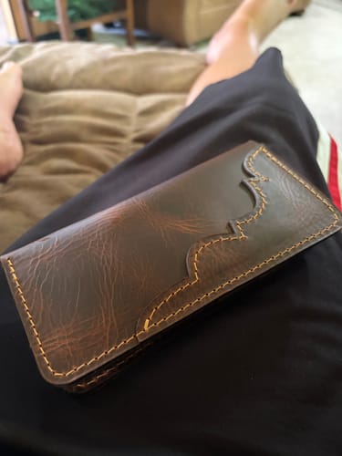Customer's brown Western Long Wallet showing early patina while resting on their lap.
